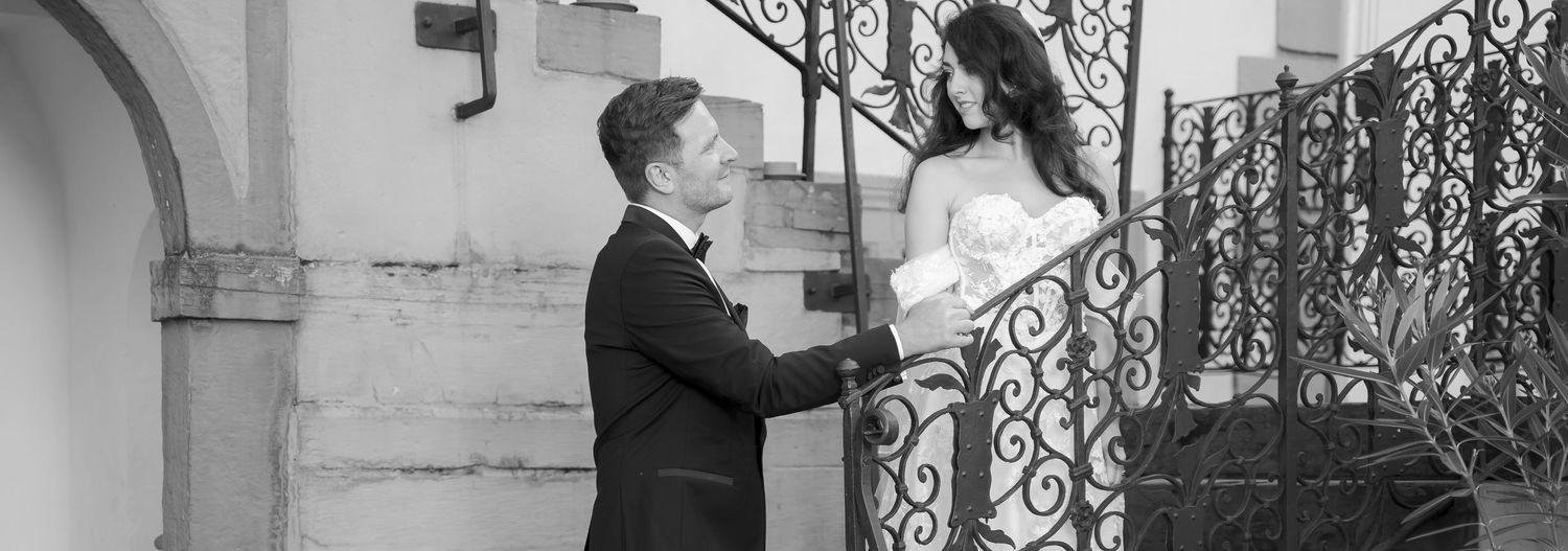 Black and white photo of bride and groom sharing a romantic moment on an ornate iron staircase.