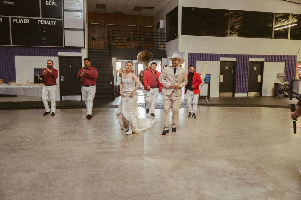 A group of men in matching red and white outfits perform a coordinated dance routine inside a large indoor venue.