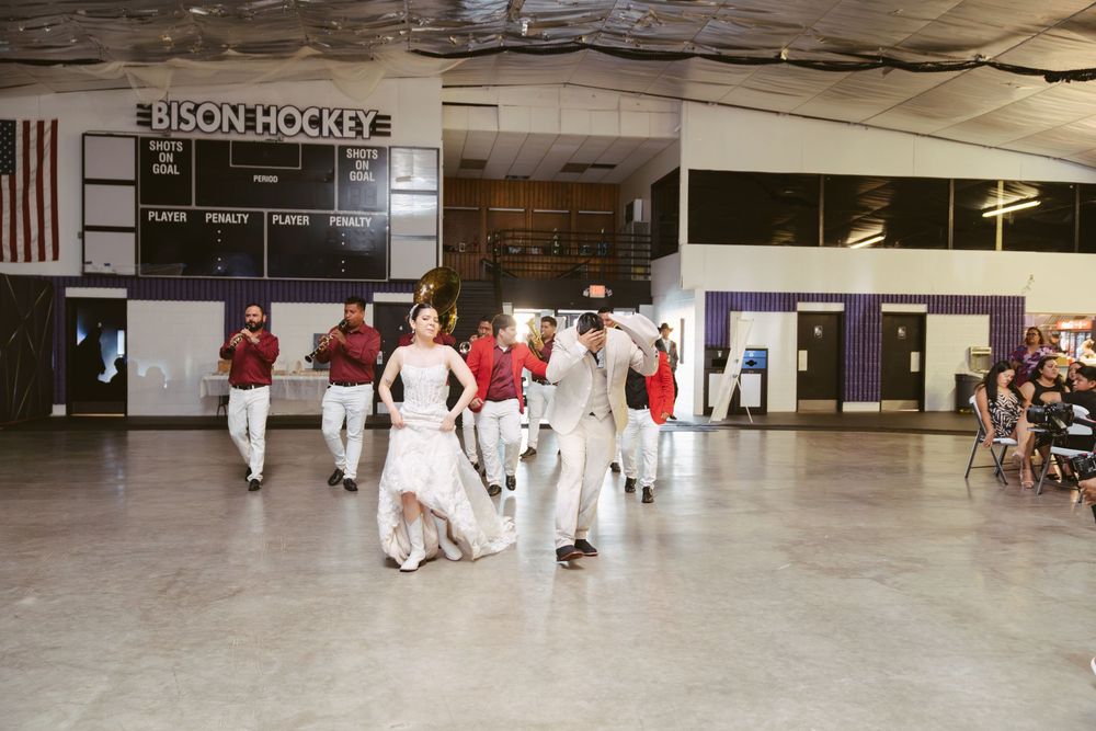 Wedding party dancing on ice rink floor under Bison Hockey scoreboard during reception celebration.