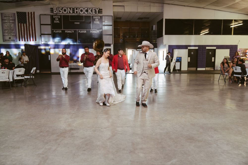 Bride and groom share first dance at Bison Hockey arena wedding reception with guests watching in background.