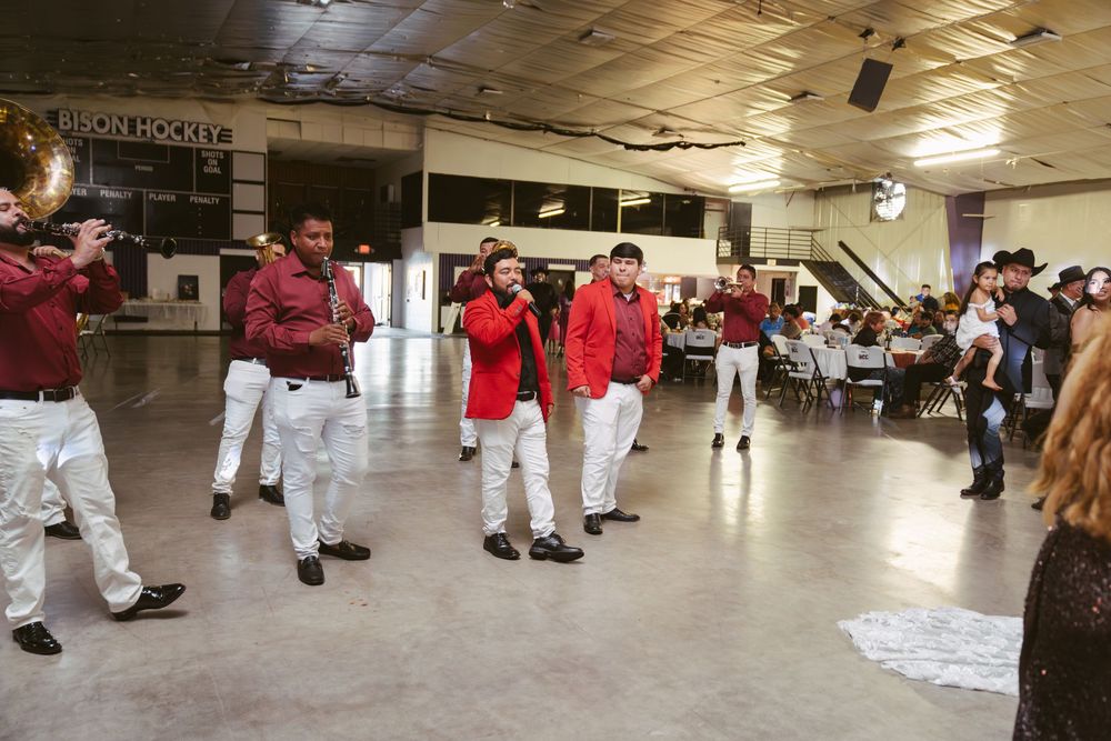 A mariachi band in red and white performs at an indoor wedding reception venue.