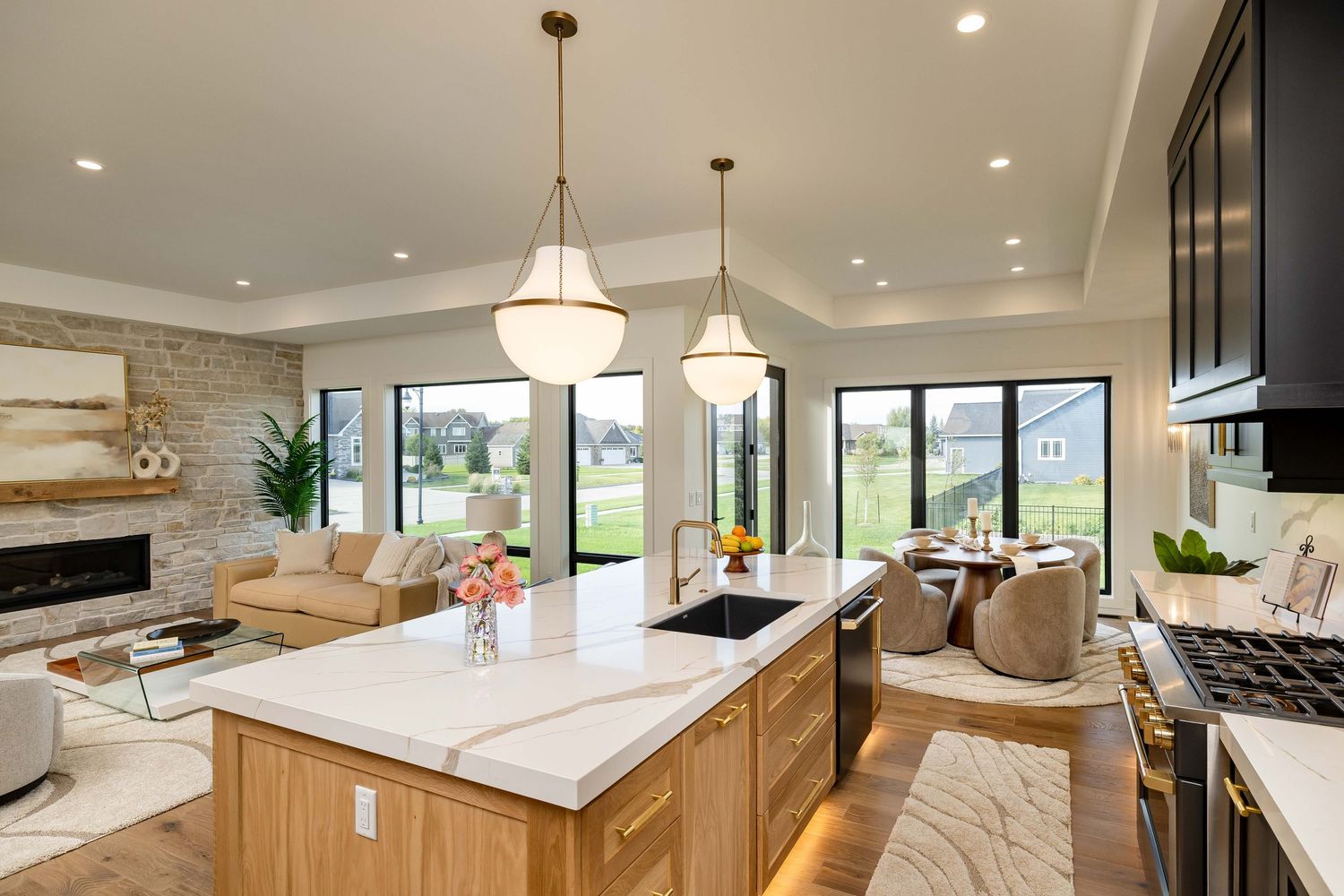 Modern open-concept kitchen with white quartz island, pendant lights, and seamless flow into living and dining areas.