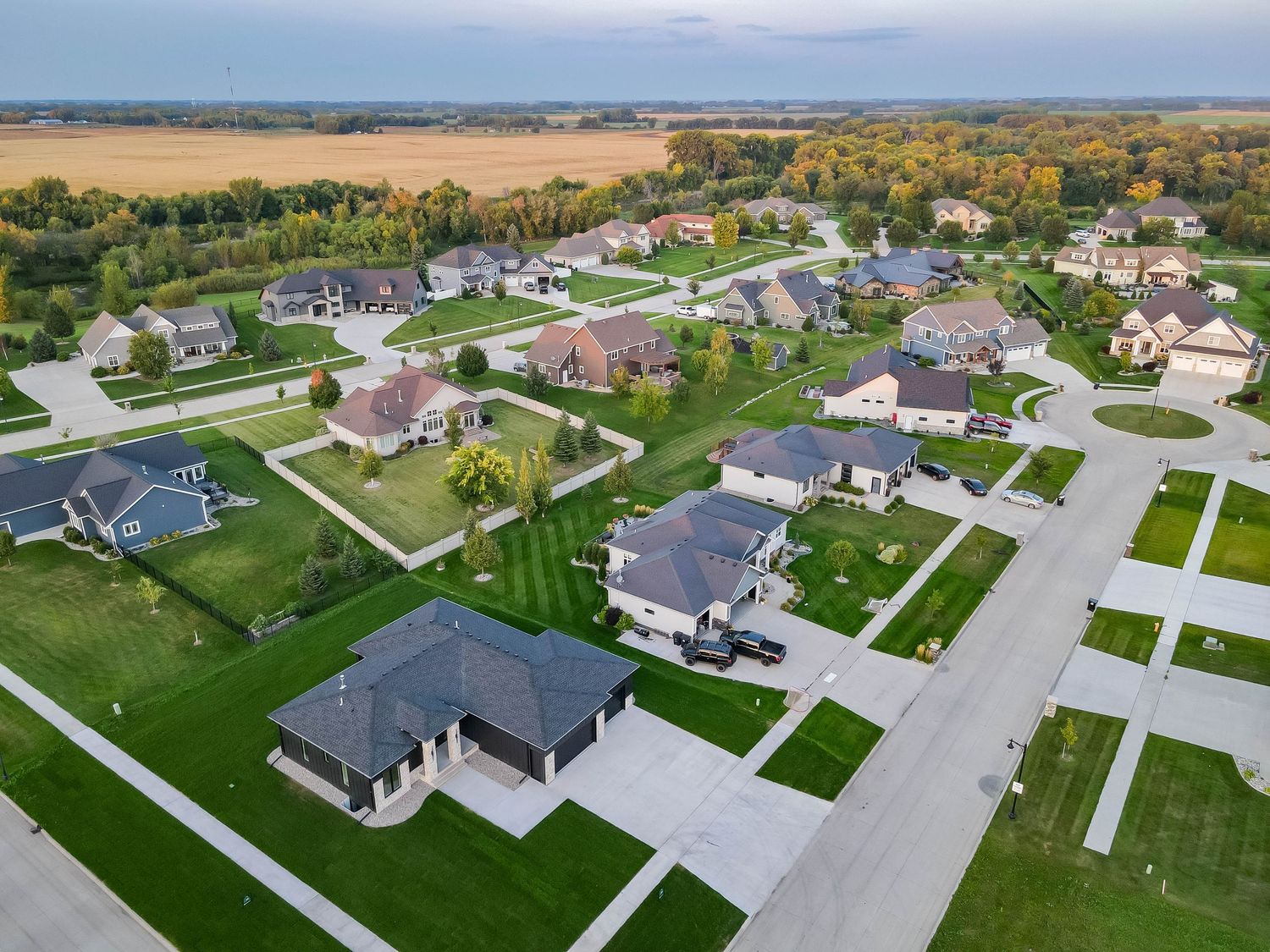 Aerial view of a modern suburban neighborhood with spacious homes, green lawns, and tree-lined streets.