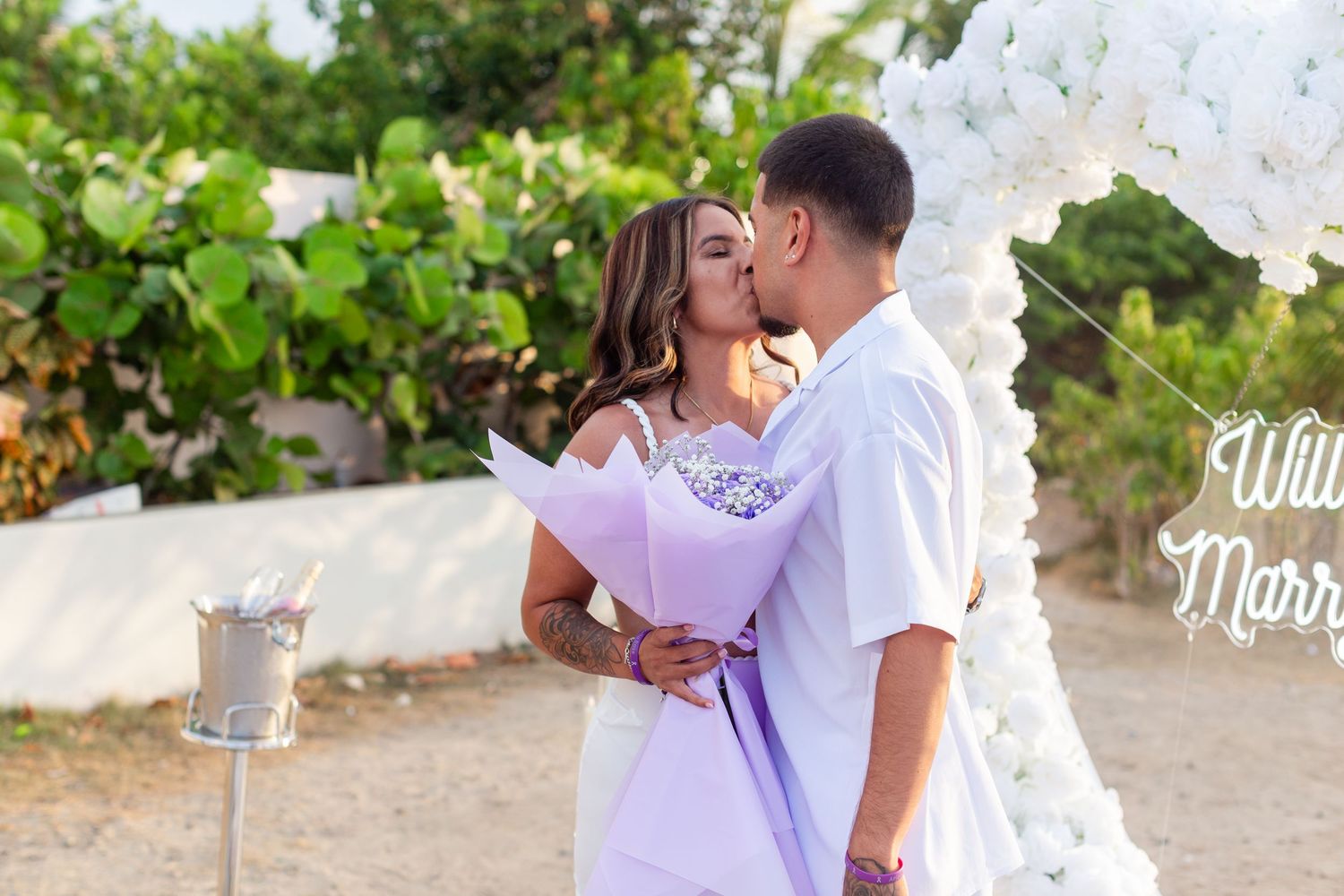 Marriage proposal. Man and woman kissing with decorative setup with white flower heart overlooking the ocean in Río Grande, Puerto Rico.