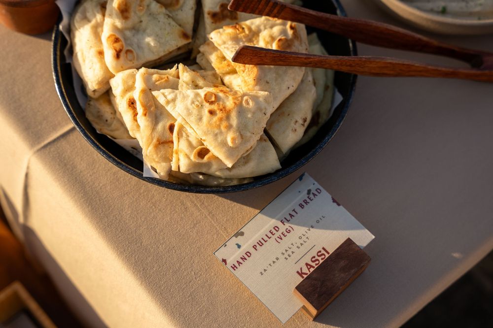 Hand-pulled flatbread triangles served in a black skillet with chopsticks at Kassi restaurant.