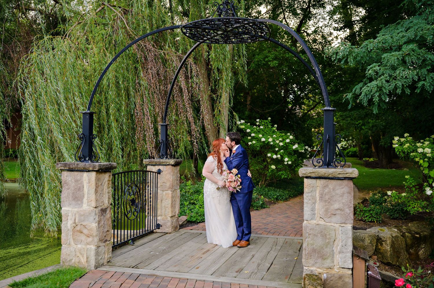 Bride and Groom kissing on the bridge after their wedding ceremony and reception at Gervasi Vineyard in the conservatory in Canton, Ohio