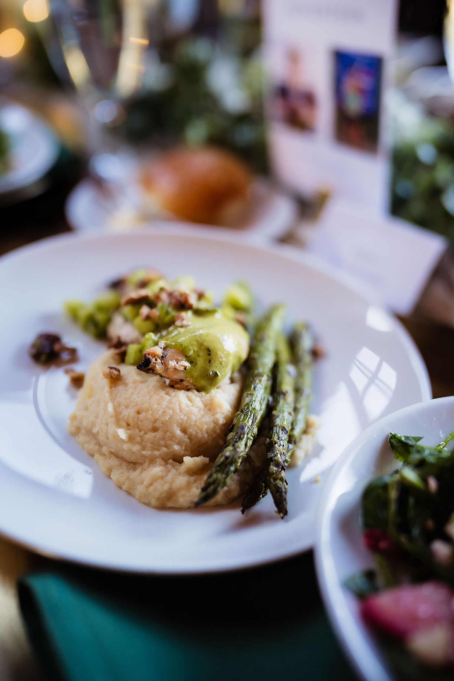 Elegant plated dish with mashed potatoes, grilled asparagus, and savory toppings served on a white plate.