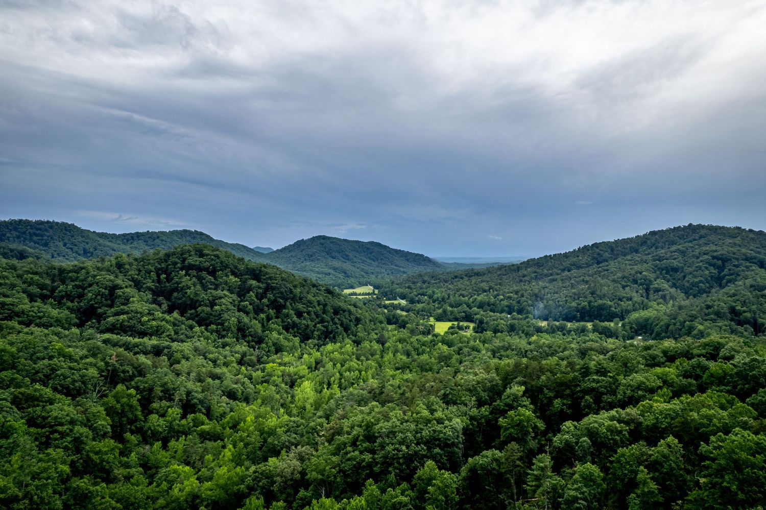 Aerial view of lush green rolling hills and mountains under a cloudy sky in a scenic forested landscape of South Carolina