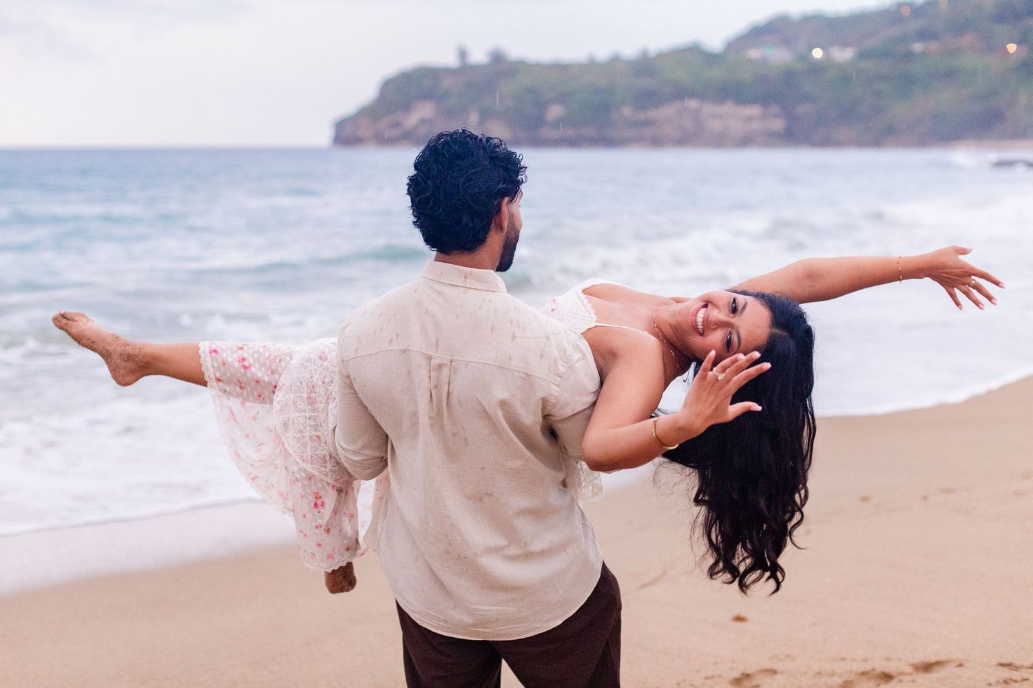 Engagement portrait on the beach. Man carrying woman, who is showing off her ring. Playa Guajataca, Isabela, Puerto Rico.