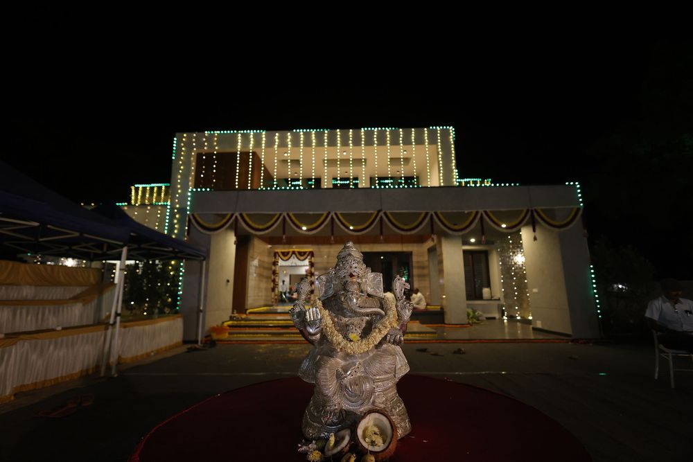 Illuminated Hindu temple at night with Ganesha statue on red carpet, decorated with green and white lights.