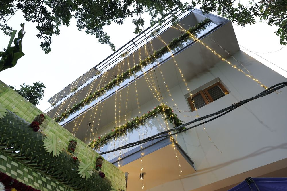 Multi-story building decorated with string lights and green garlands cascading down its white facade.