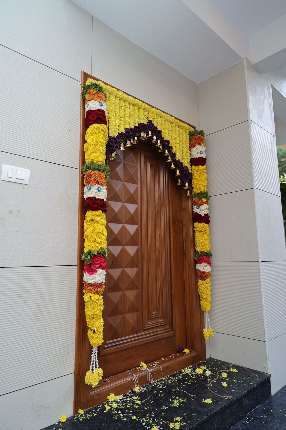 Traditional wooden door adorned with colorful marigold and flower garlands for an Indian housewarming ceremony.