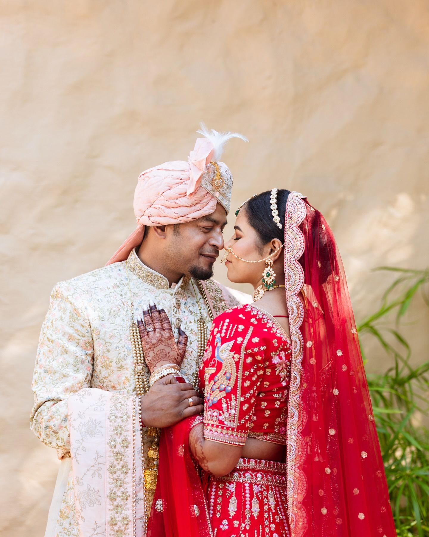 South Indian couple in traditional wedding attire sharing a joyful moment outdoors with lush greenery backdrop.