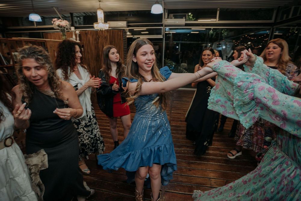 Women dancing joyfully at a lively party, wearing colorful dresses in a festive indoor venue.