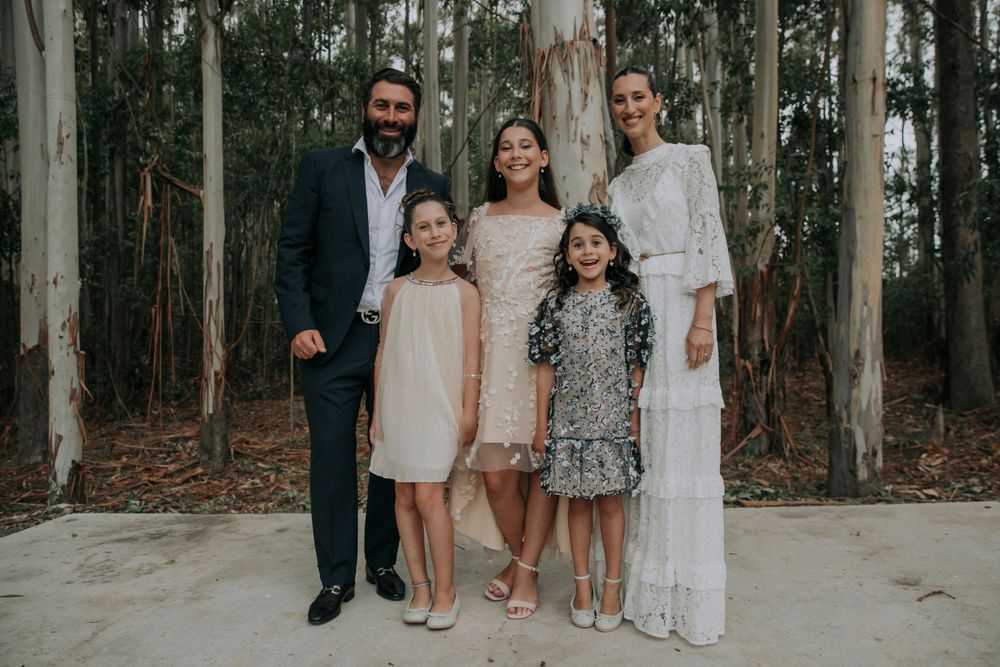 A formal portrait of a family group standing together in a eucalyptus forest.
