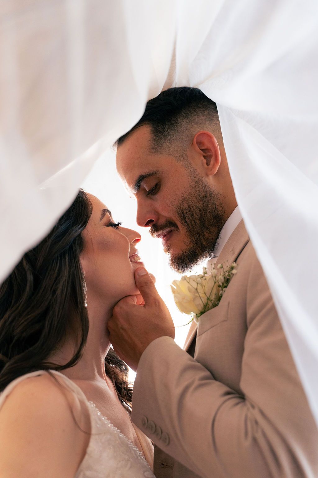 Close-up wedding portrait of a bride and groom sharing an intimate moment beneath the bridal veil, photographed by Okatastudio