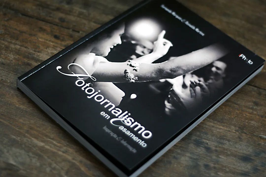 Black and white photography book titled Fotojornalismo lying on a wooden surface.