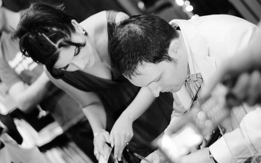 Black and white photo of two people leaning over a table at a formal event.