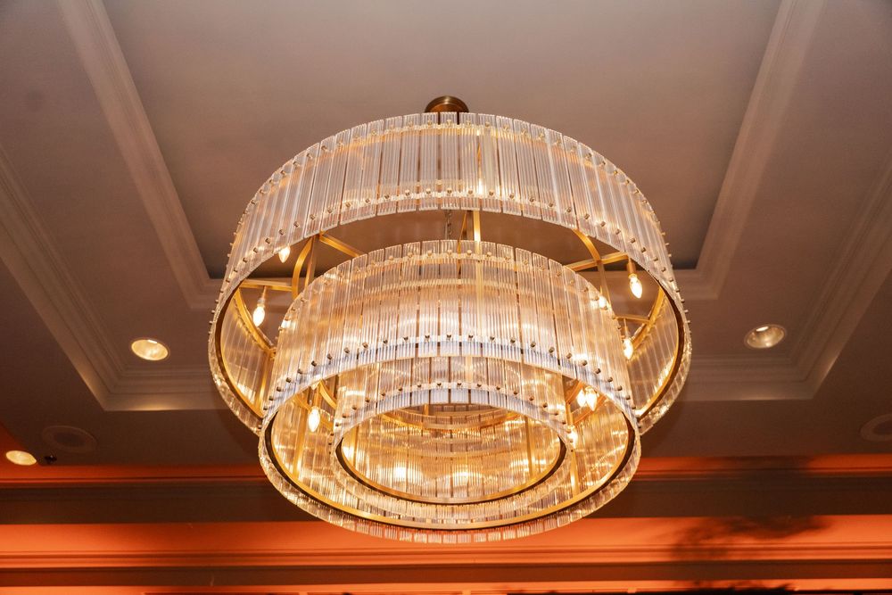 Elegant multi-tiered crystal chandelier with gold frame hanging from ornate ceiling in luxury interior.