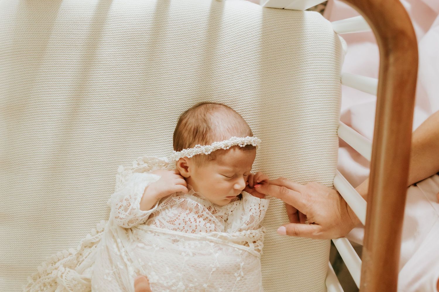 Sleeping newborn baby girl in white lace outfit and floral headband cradled in parents arms. nj Cranford Westfield nj scotch plains fan wood