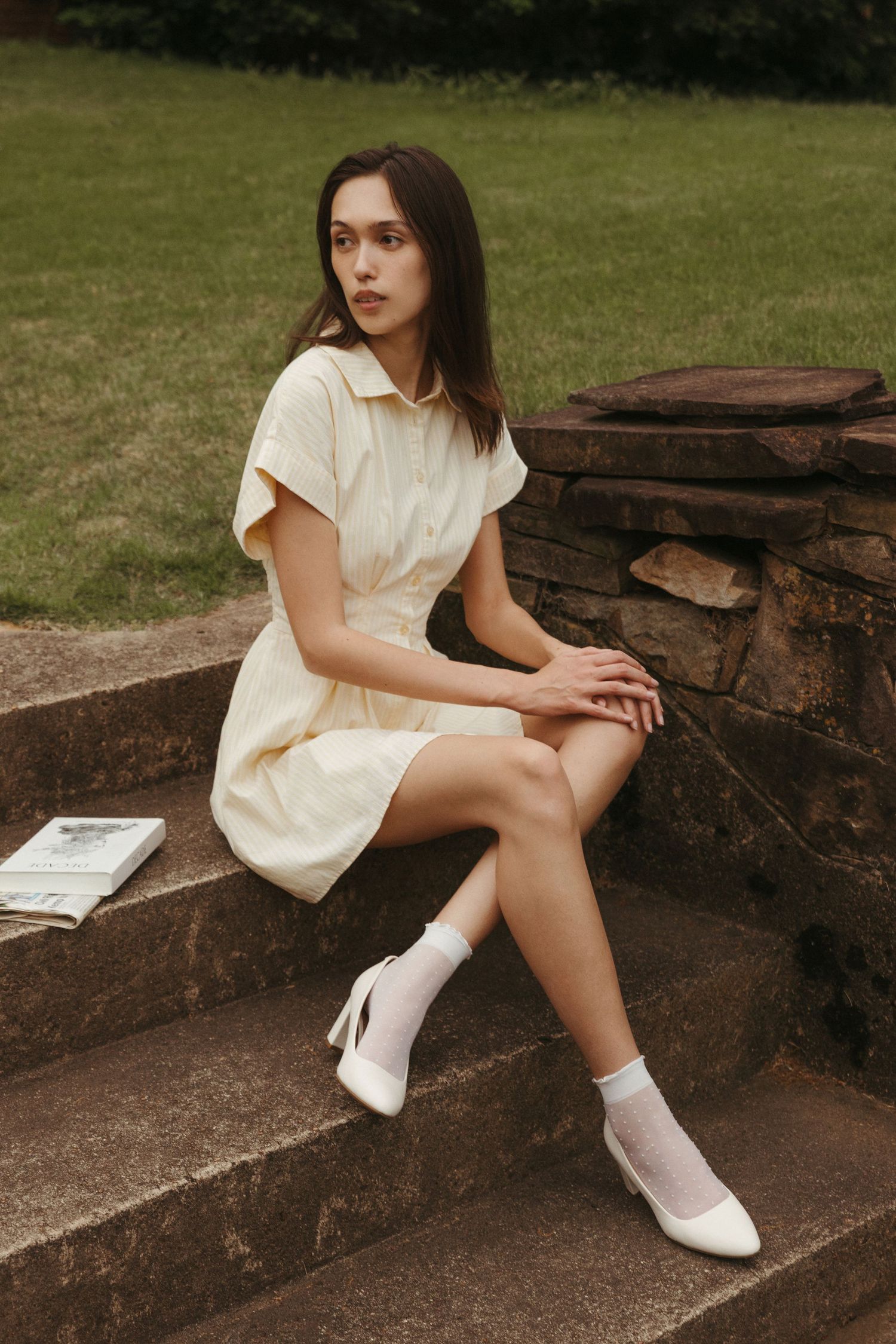 Editorial model sitting on steps in front of historic Southern home and wearing butter yellow dress, Atlanta fashion photography