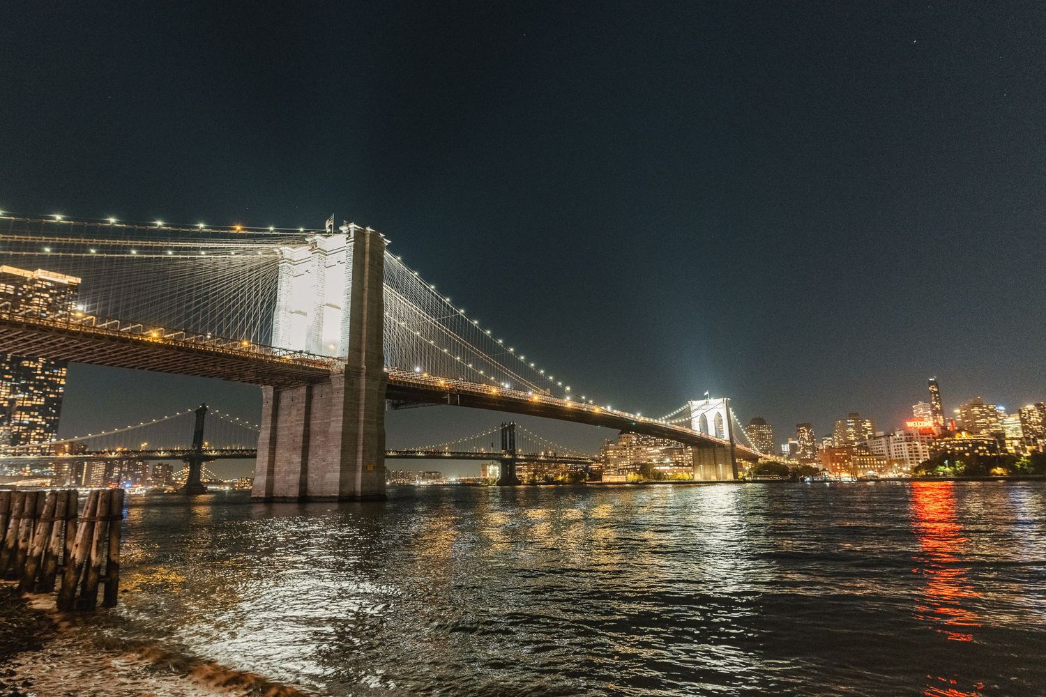 Ponte di Brooklyn di notte con insegna luminosa "Welcome" sulla riva