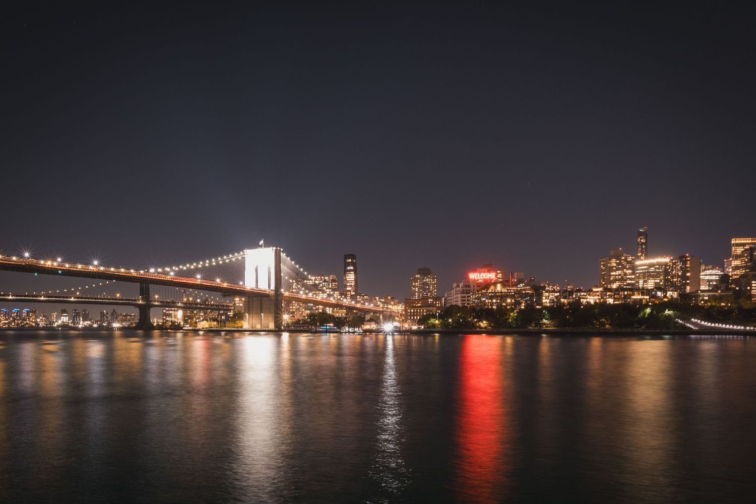 Ponte di Brooklyn illuminato di notte con lo skyline di Manhattan sullo sfondo