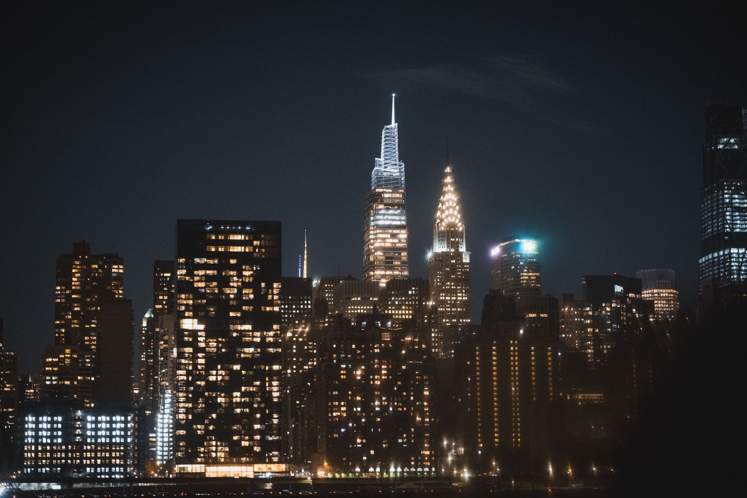 Ponte di Brooklyn con lo skyline di Manhattan illuminato di notte visto dall'acqua