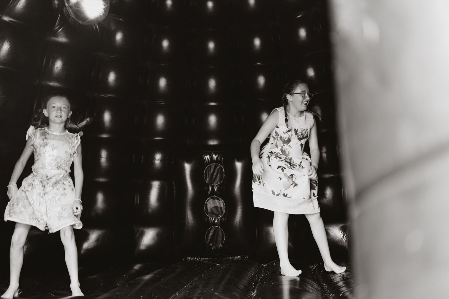 Two young girls in dresses dancing on bouncy castle at Moat Hall Barns