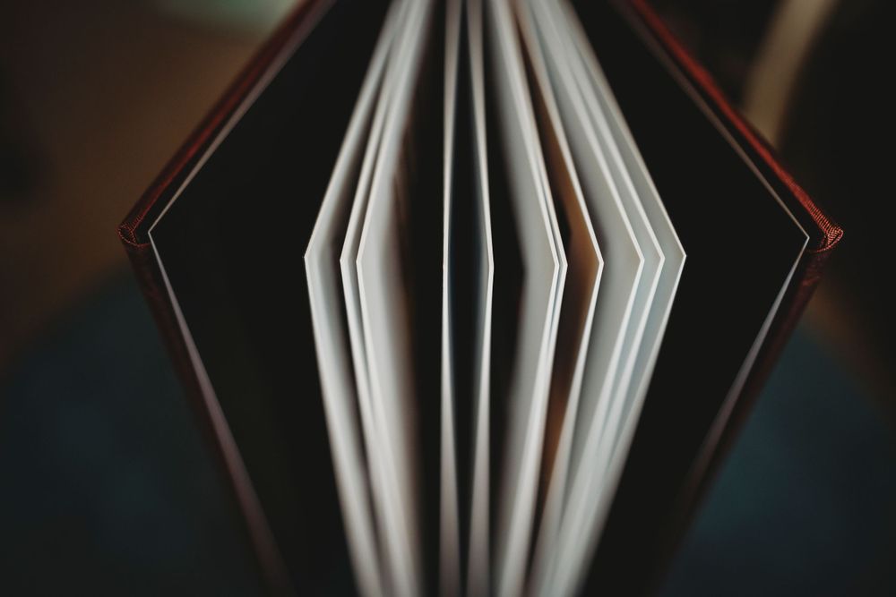 Close-up view of an open book's pages fanned out against a dark background.