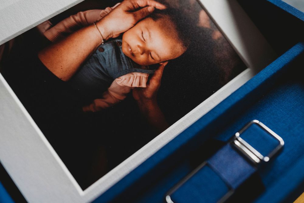A photograph lying beside a blue leather strap showing an intimate portrait in moody lighting.