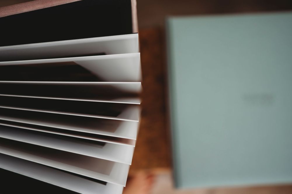Close-up view of fanned white book pages against a blurred teal background.