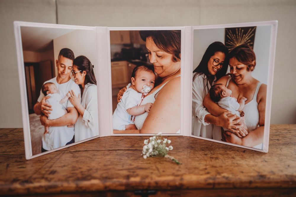 Three portrait photographs displayed on wooden surface with small white flowers.