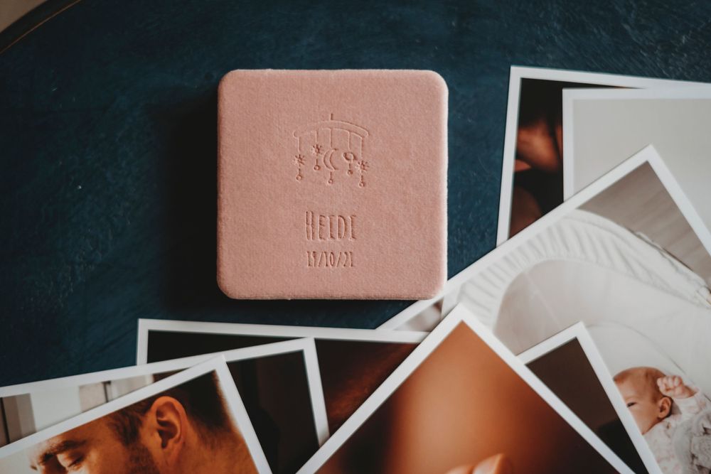 Collection of photographs scattered around a pink photo box on dark surface.