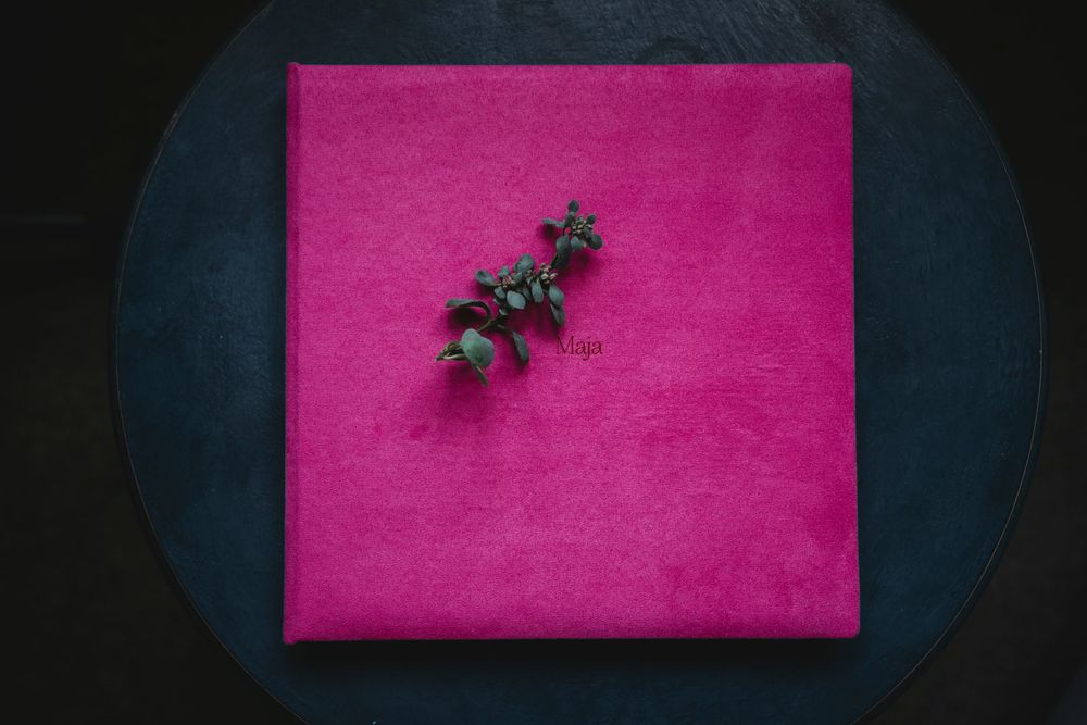 Small dried flowers on bright pink photo album cover against dark background.
