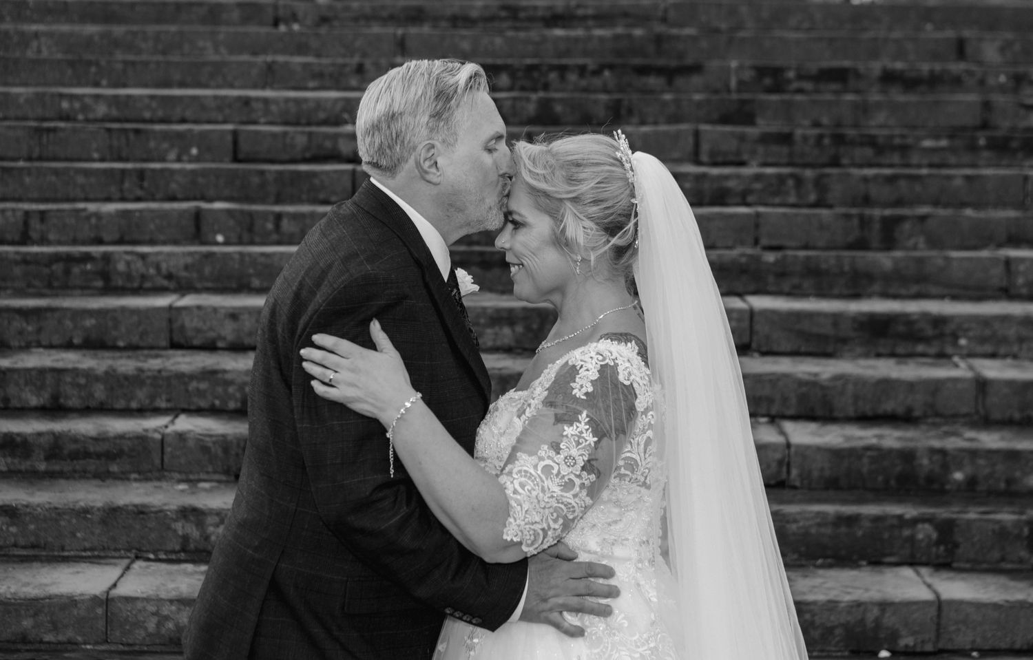 A couple shares romantic dance moments at their wedding reception in dimly lit venue with artistic framing.