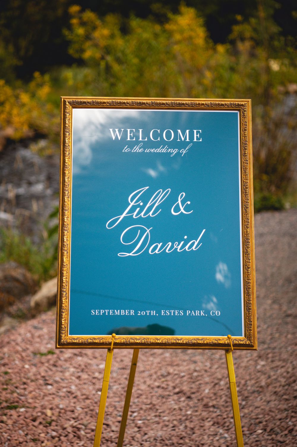 Gold framed wedding welcome sign for Jill & David on blue background, September 20th, Estes Park, CO.