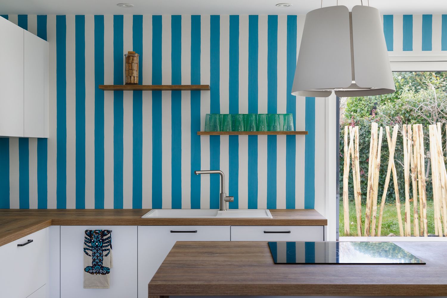 Cuisine lumineuse dotée d'une crédence aux rayures verticales bleues et blanches saisissantes, de plans de travail en bois