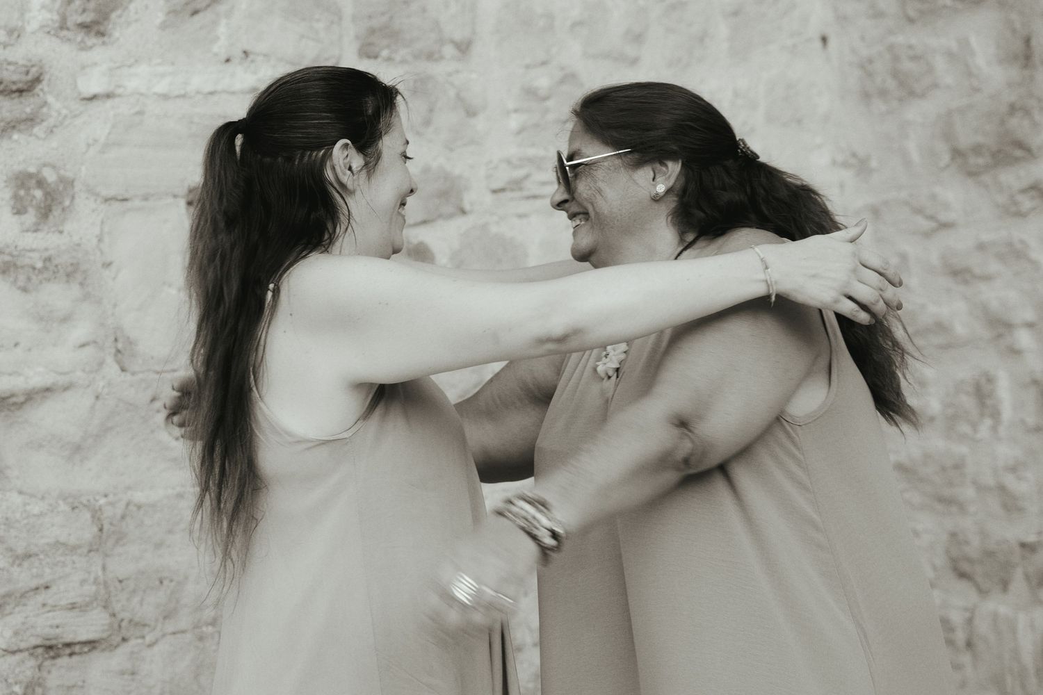Portrait en noir et blanc d’une mère et de sa fille adulte qui se regardent en souriant aux remparts de Trets.