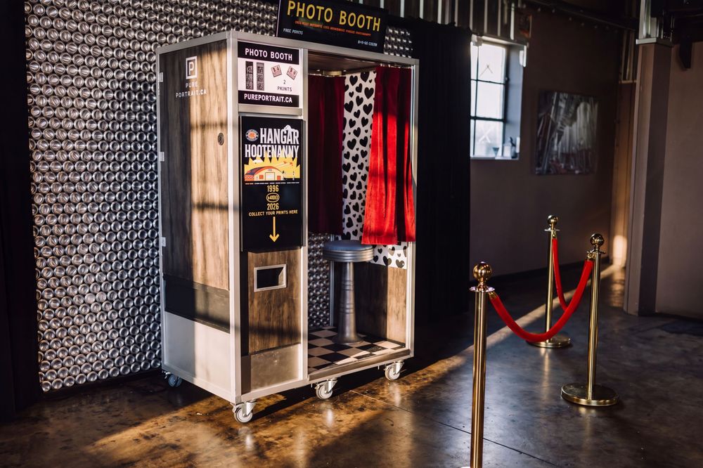 Vintage enclosed photo booth with red curtain and velvet rope on a polished concrete floor at an event venue wild rose brewery