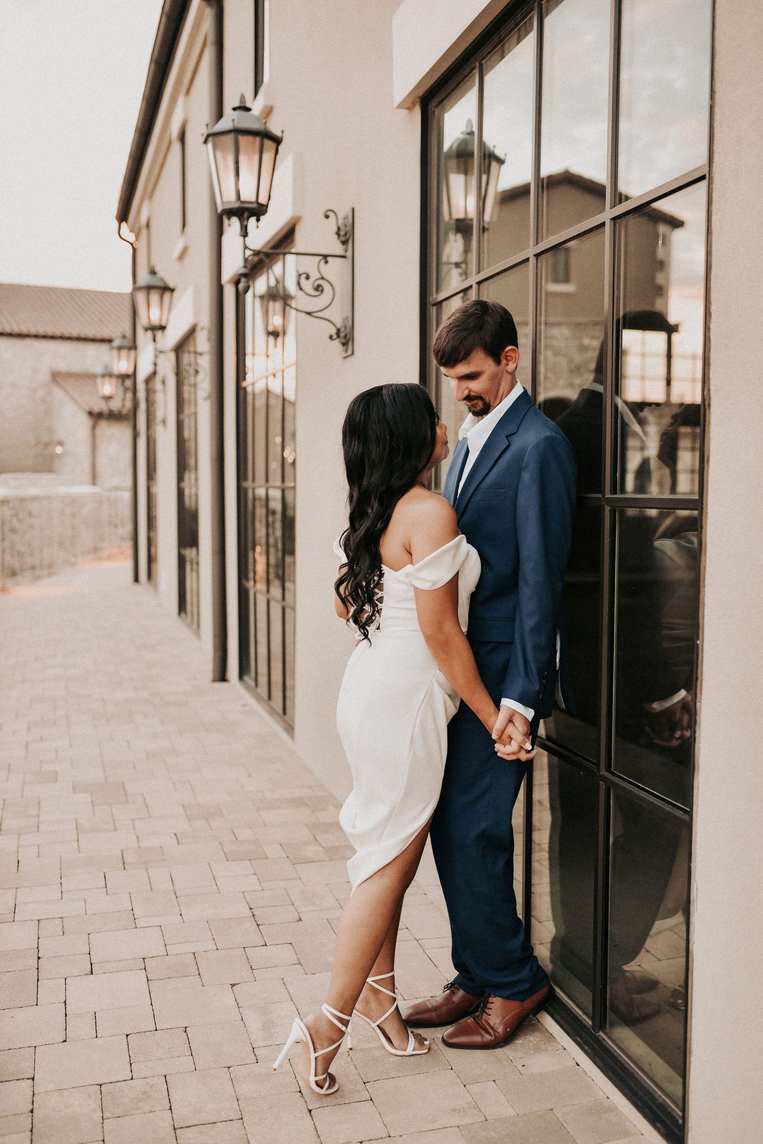 Modern engagement posing against the glass doors and stone architecture at Chapel at Palacios