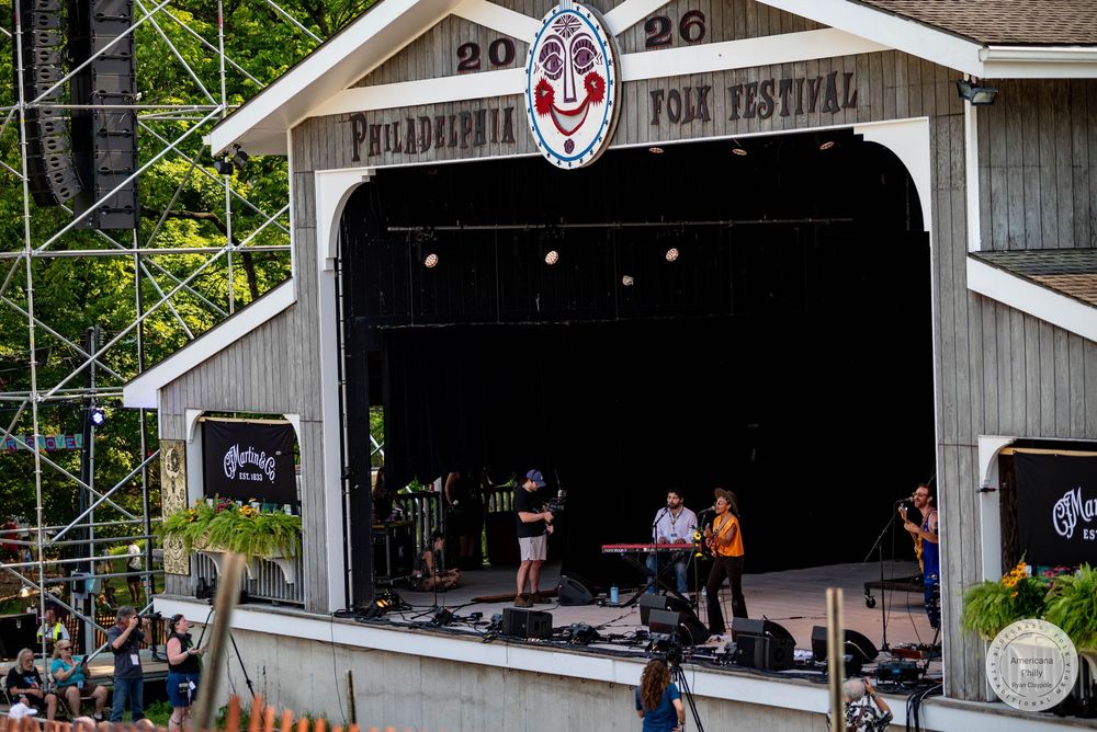 Live band performs on stage at the Philadelphia Folk Festival outdoor amphitheater during a summer evening concert.