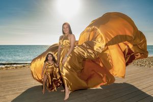 Golden fabric billows dramatically against sunset beach backdrop.