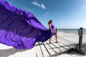 Dramatic purple fabric flowing in the wind on a beach boardwalk.