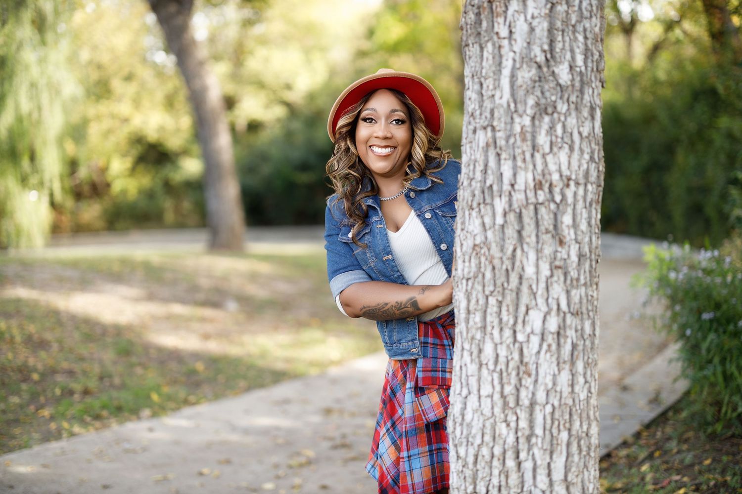 Casual outdoor photoshoot near a large tree trunk in a natural park setting.