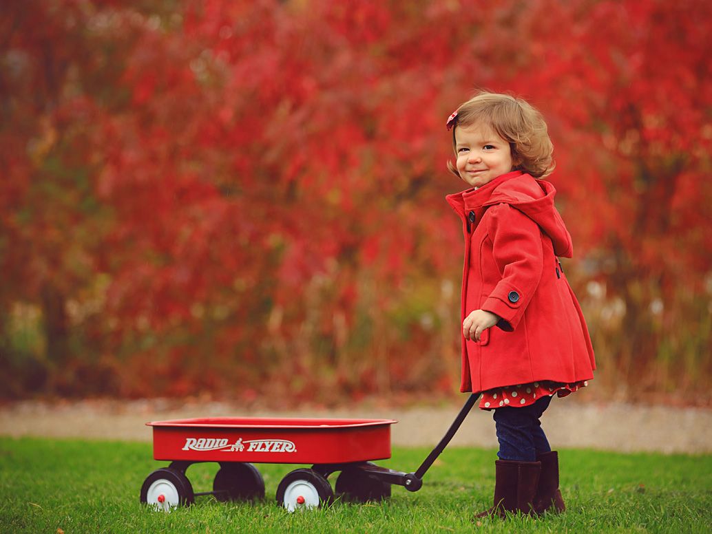 Little girl with red wagon and coat at Matthaei Botanical Gardens in Ann Arbor; family portraits by Brighton, MI family photographer