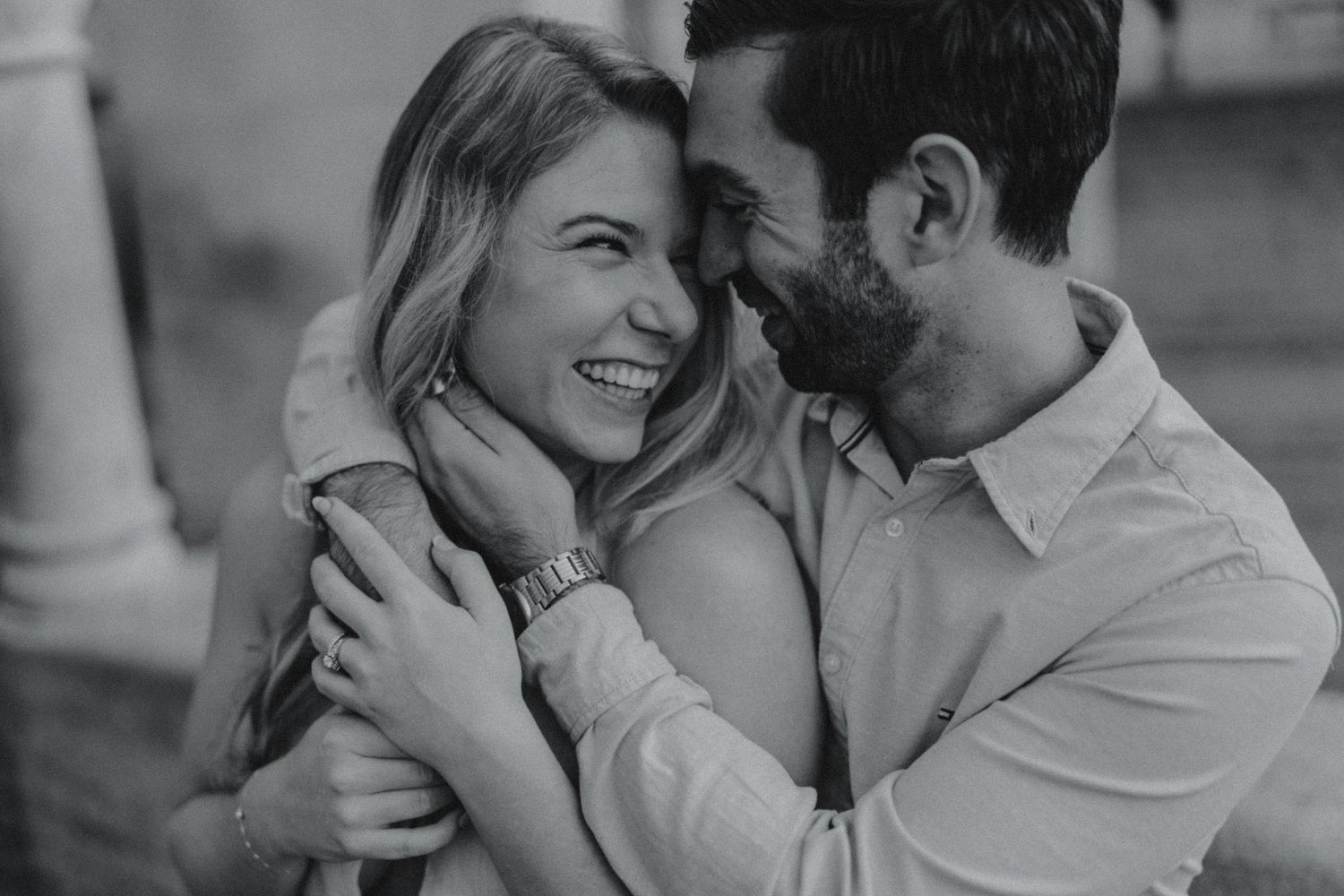 Black and white photo of a laughing couple embracing and sharing a joyful intimate moment together.