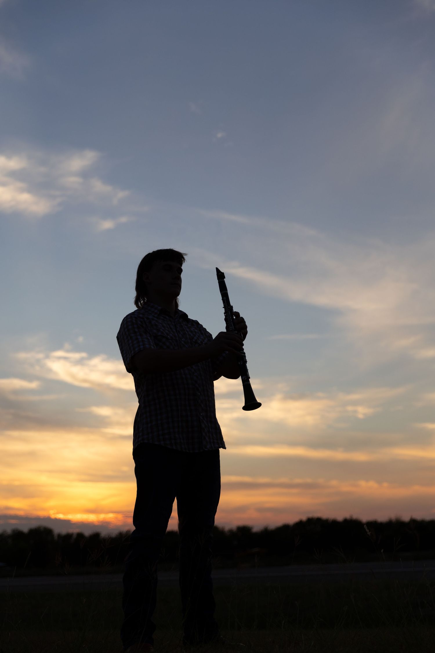 Silhouette image of a man holding a clarinet.