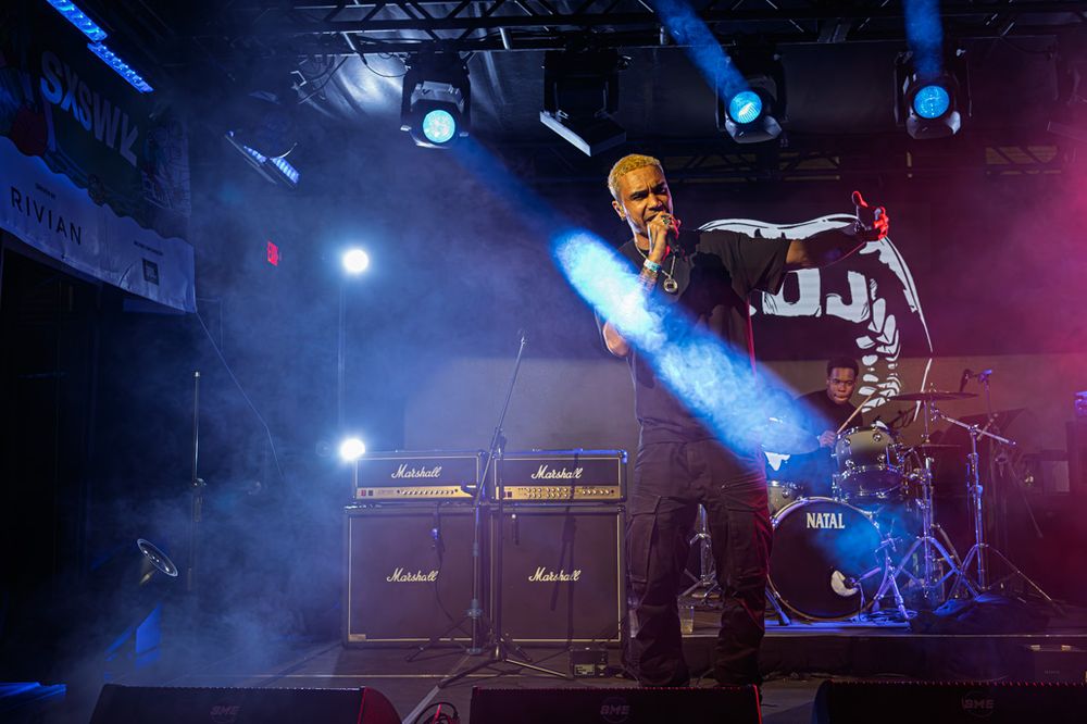 Rock band performs on stage with Marshall amps, dramatic blue lighting, and fog effects at a live concert venue.