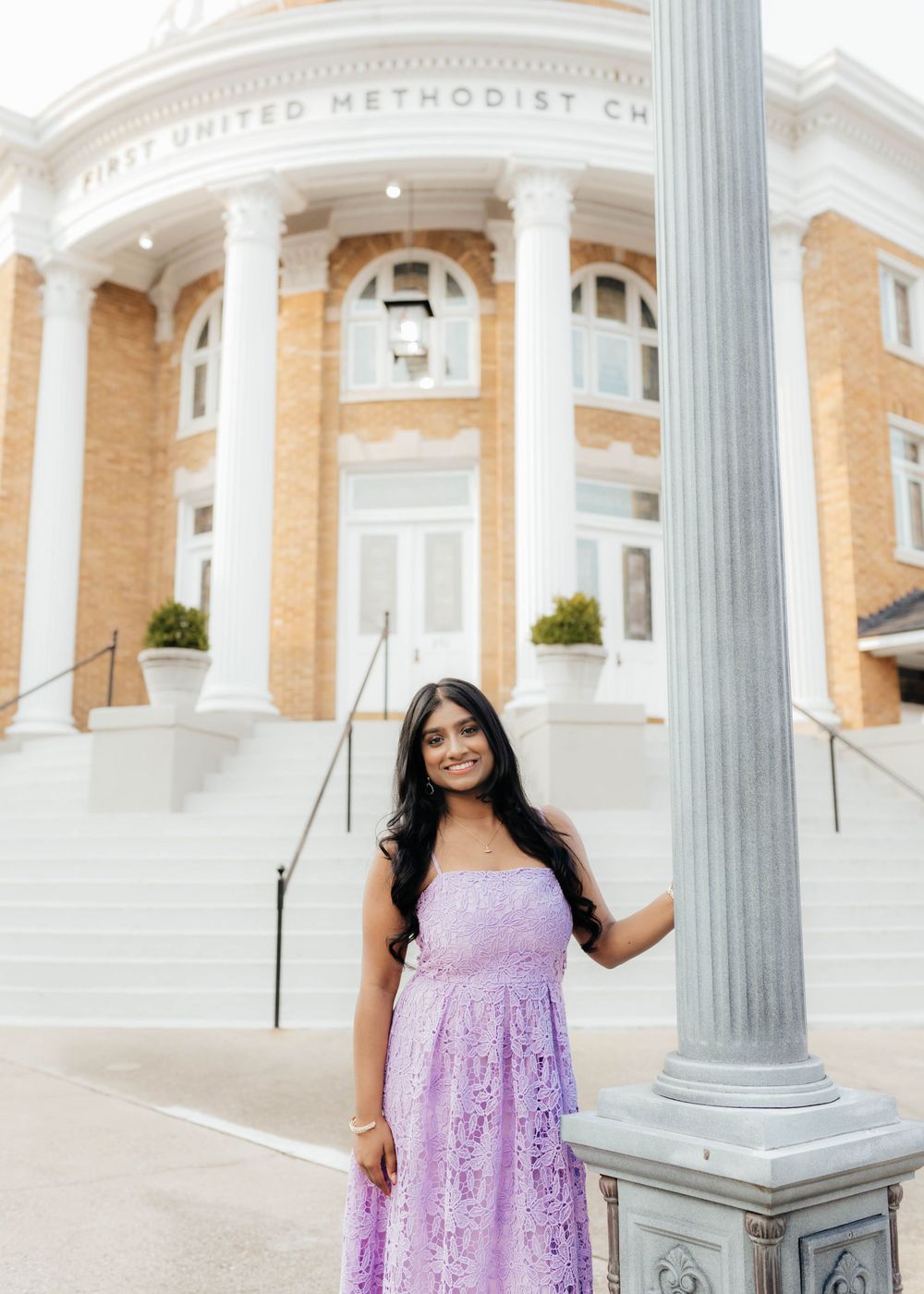 Young woman in lavender lace dress posing by a column outside First United Methodist Church.